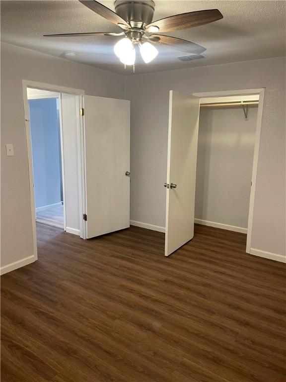 unfurnished bedroom with dark hardwood / wood-style flooring, a closet, and ceiling fan