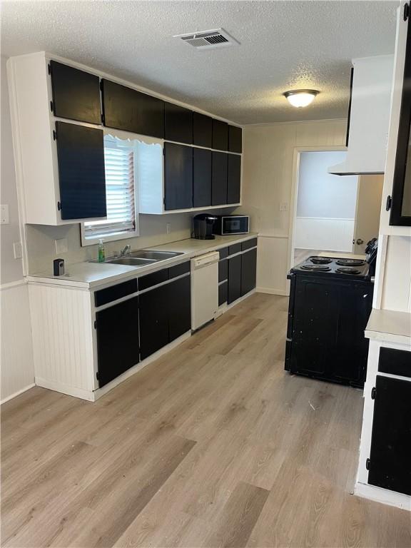 kitchen featuring a textured ceiling, sink, dishwasher, light hardwood / wood-style floors, and black electric range oven