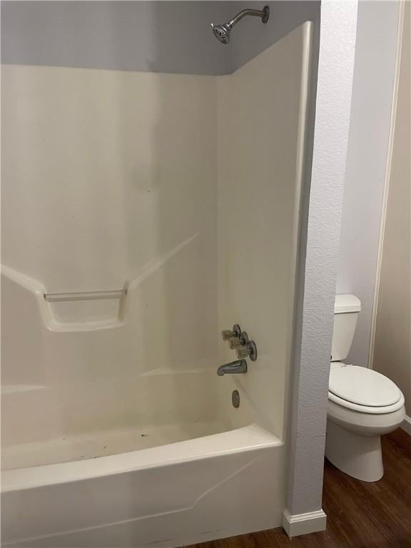 bathroom with wood-type flooring, toilet, and shower / tub combination