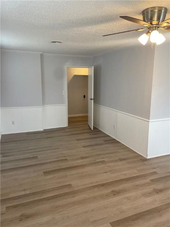 spare room with ceiling fan, hardwood / wood-style floors, a textured ceiling, and ornamental molding