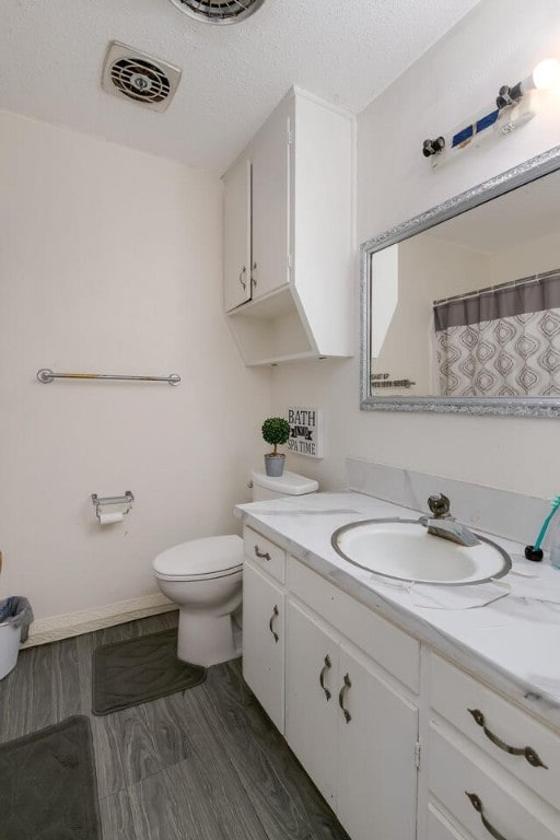 bathroom featuring hardwood / wood-style flooring, vanity, toilet, and a textured ceiling