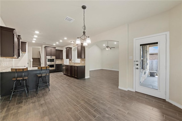 kitchen with stainless steel appliances, dark hardwood / wood-style floors, hanging light fixtures, and backsplash