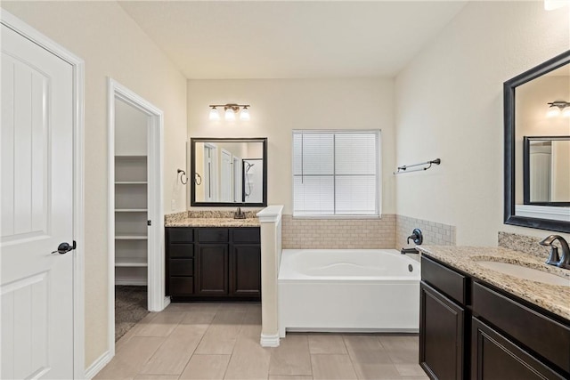 bathroom featuring a tub to relax in, tile patterned floors, and vanity