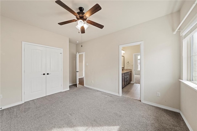 unfurnished bedroom with connected bathroom, ceiling fan, a closet, and light carpet