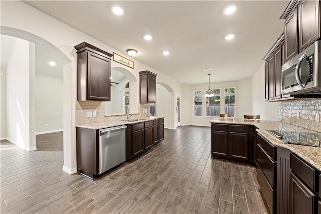 kitchen with decorative light fixtures, decorative backsplash, wood-type flooring, and appliances with stainless steel finishes