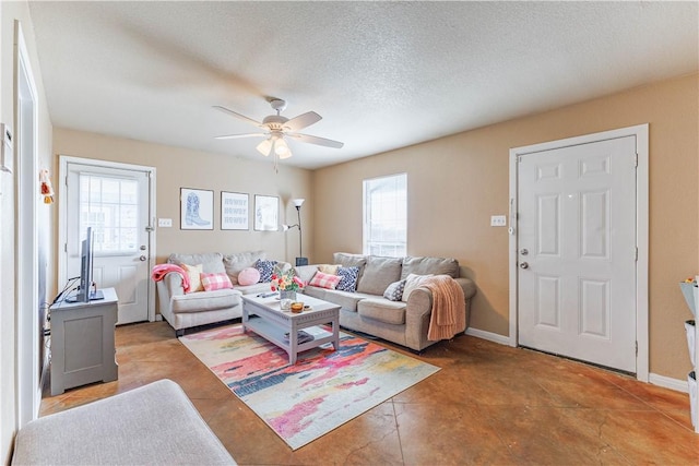 living room featuring a ceiling fan, a textured ceiling, and baseboards