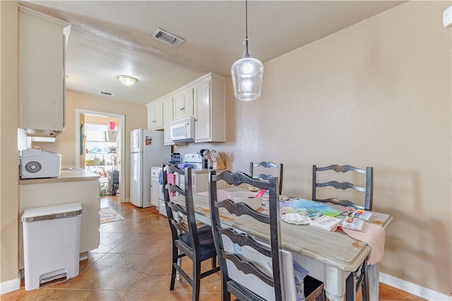 dining space featuring light tile patterned floors, baseboards, visible vents, and a textured ceiling