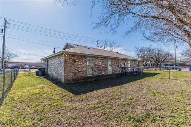 view of side of home with brick siding, a fenced backyard, and a yard