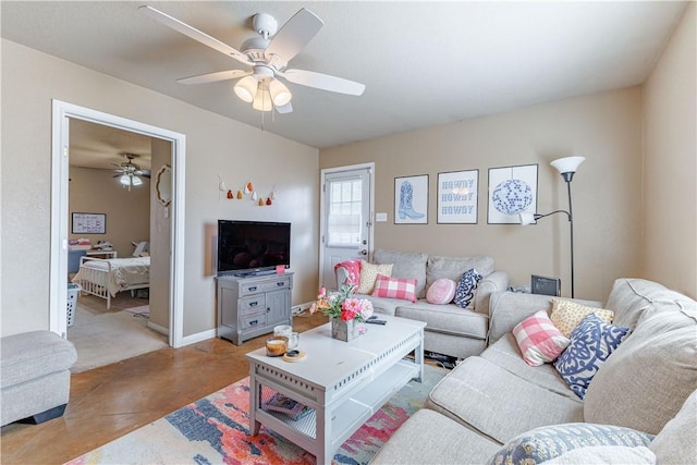 living area featuring concrete flooring, ceiling fan, and baseboards