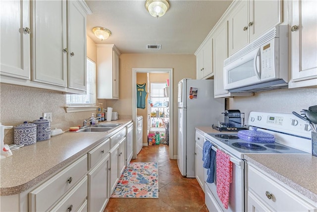 kitchen featuring white appliances, visible vents, a sink, and white cabinetry