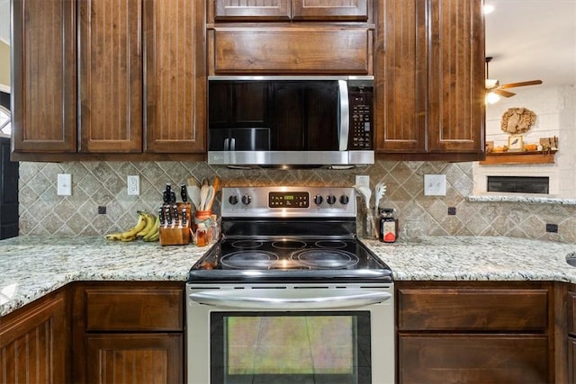 kitchen with tasteful backsplash, stainless steel appliances, ceiling fan, and light stone countertops