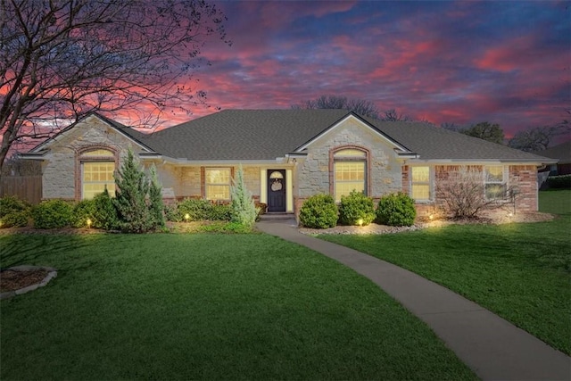 single story home with stone siding, roof with shingles, and a front lawn