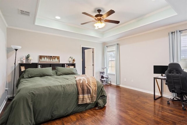 bedroom with a raised ceiling, multiple windows, wood finished floors, and ornamental molding