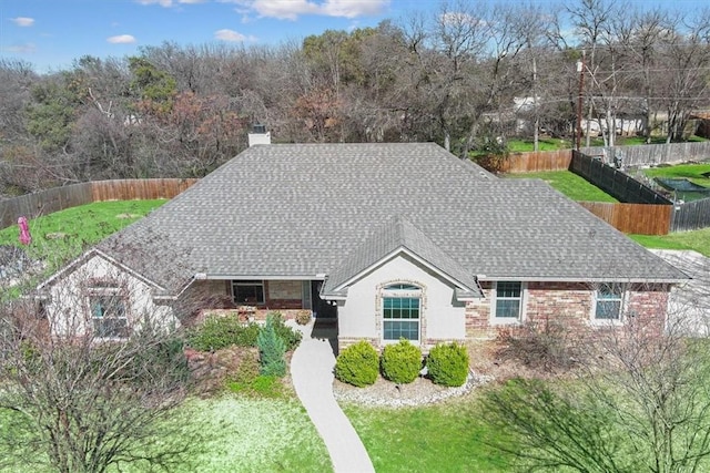 ranch-style home featuring a front yard, fence, roof with shingles, and a chimney