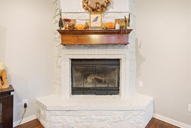 room details with wood finished floors, baseboards, and a large fireplace