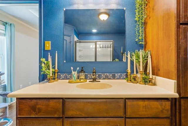 bathroom featuring vanity, crown molding, a textured wall, and a stall shower