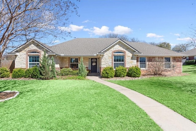 ranch-style home featuring a front yard, brick siding, and roof with shingles