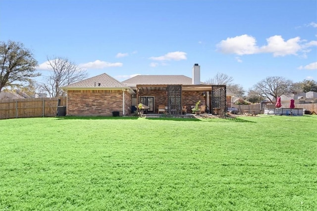 back of property featuring a lawn, brick siding, and a fenced backyard