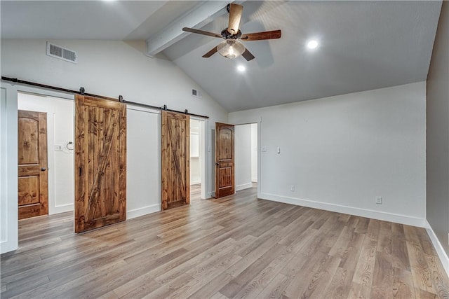 unfurnished bedroom featuring beamed ceiling, ceiling fan, a barn door, and light hardwood / wood-style floors