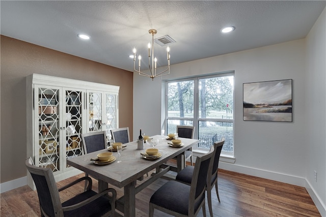 dining room with a chandelier, a textured ceiling, and hardwood / wood-style flooring