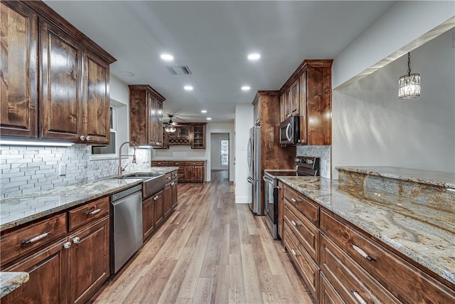 kitchen with ceiling fan with notable chandelier, sink, hanging light fixtures, appliances with stainless steel finishes, and light hardwood / wood-style floors