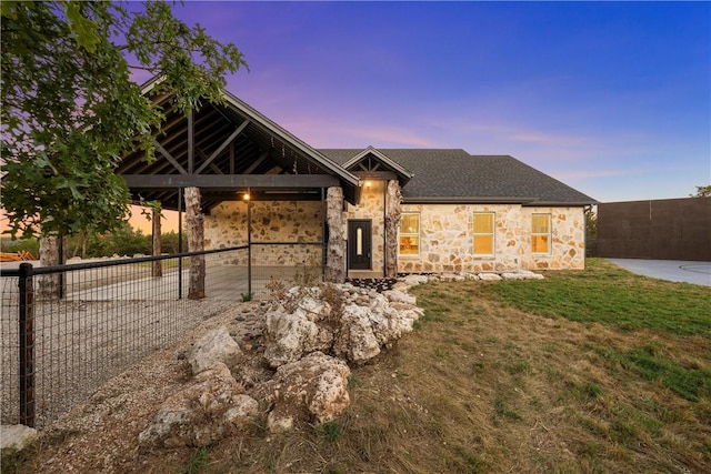 view of front facade featuring a yard, stone siding, and fence