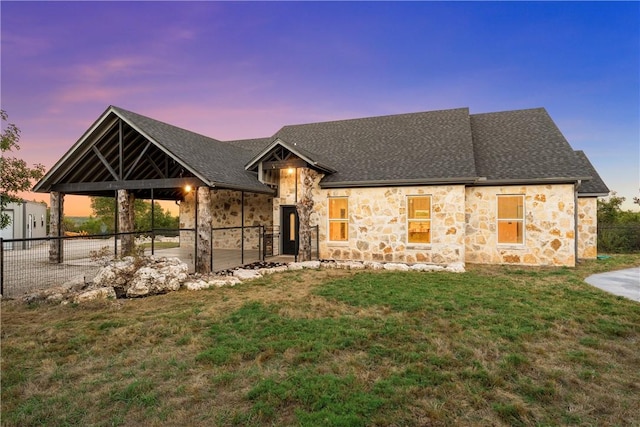 view of front facade with a shingled roof, fence, and a front lawn