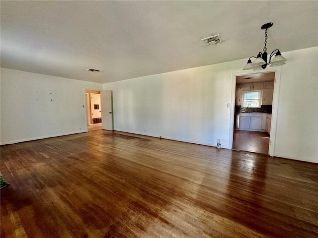 spare room featuring a notable chandelier, dark hardwood / wood-style floors, and sink