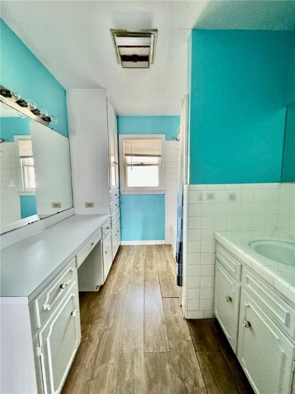 bathroom with hardwood / wood-style floors, vanity, shower / tub combo, and tile walls