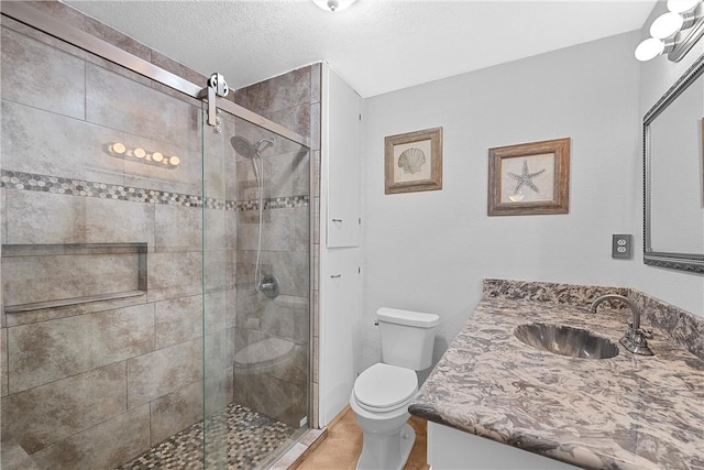 bathroom with a textured ceiling, vanity, toilet, and walk in shower