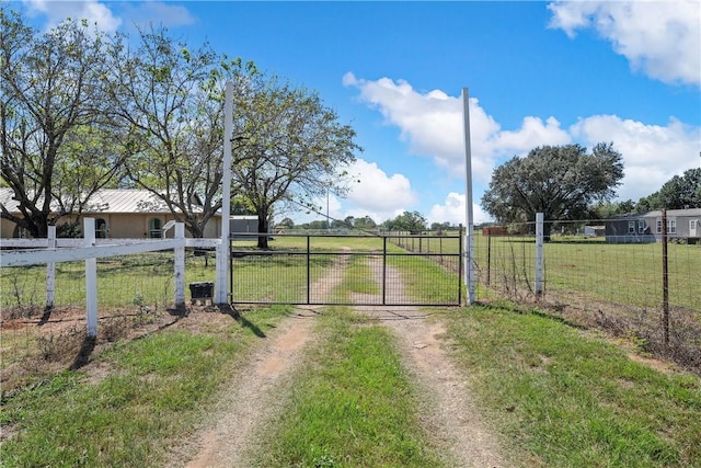 view of gate with a yard and a rural view