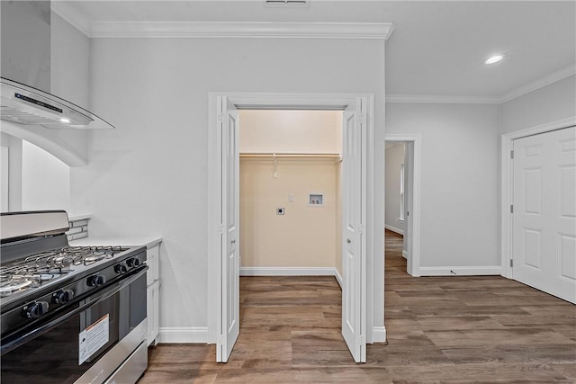 kitchen featuring gas stove, wood-type flooring, wall chimney range hood, and crown molding