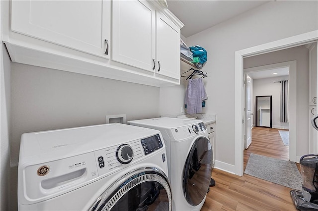 laundry area featuring separate washer and dryer, light hardwood / wood-style flooring, and cabinets