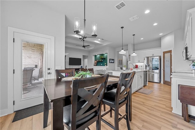 dining room featuring light hardwood / wood-style flooring, ceiling fan with notable chandelier, and sink