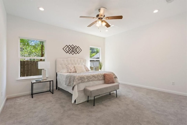 carpeted bedroom featuring multiple windows and ceiling fan