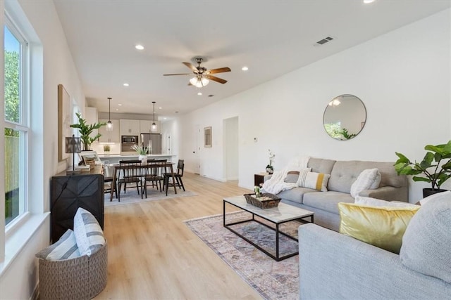 living room with ceiling fan and light wood-type flooring