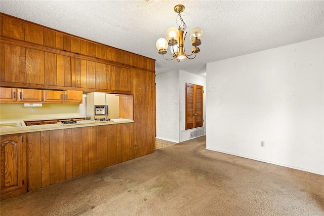 kitchen with a textured ceiling, a notable chandelier, decorative light fixtures, and dark colored carpet