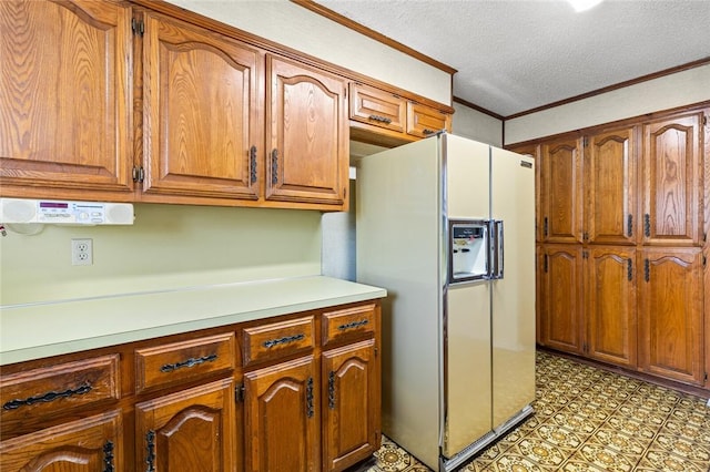 kitchen featuring crown molding, white refrigerator with ice dispenser, and a textured ceiling