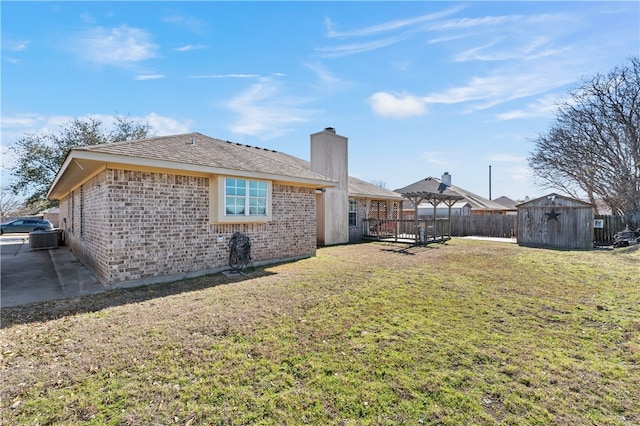 exterior space with fence, a yard, a storage shed, an outdoor structure, and brick siding