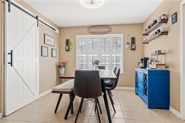 dining space featuring light tile patterned floors, baseboards, and a barn door