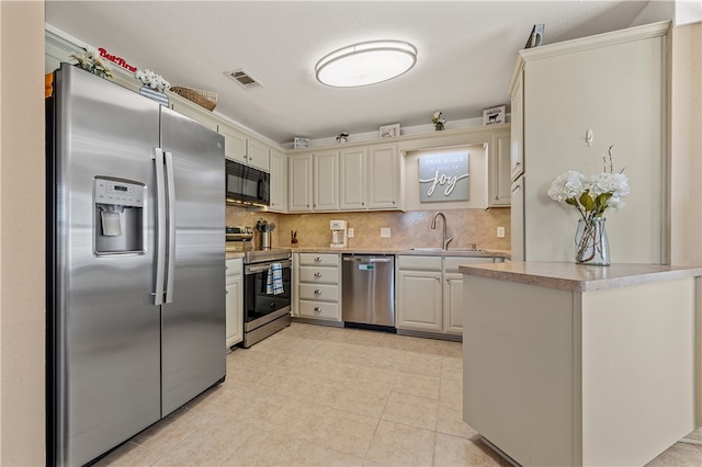 kitchen with visible vents, backsplash, stainless steel appliances, and a sink