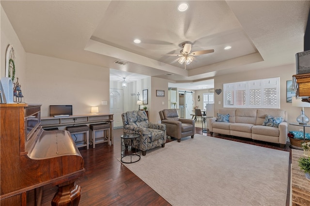 living area featuring visible vents, dark wood-style floors, recessed lighting, a raised ceiling, and ceiling fan