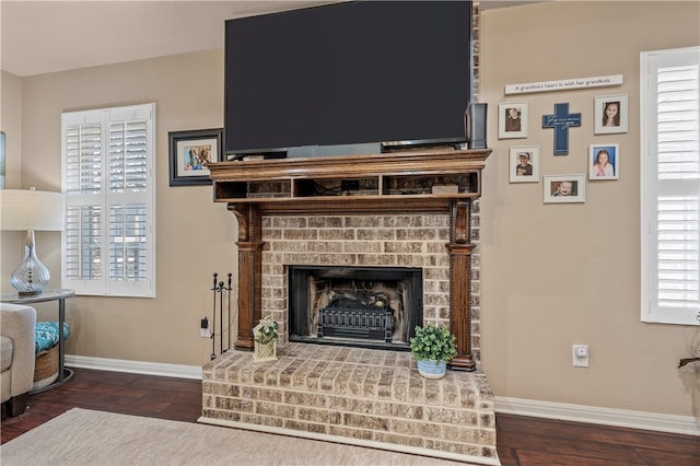 living area featuring a brick fireplace, wood finished floors, and baseboards