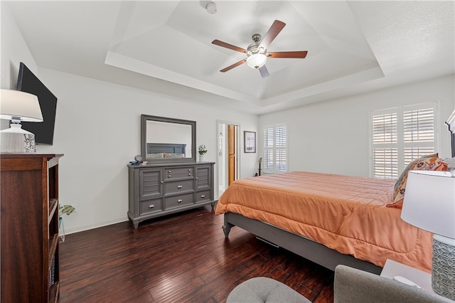 bedroom with baseboards, a raised ceiling, ceiling fan, and hardwood / wood-style flooring