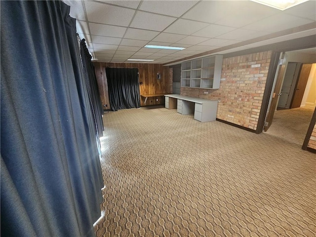 interior space featuring light carpet, wood walls, a drop ceiling, and built in study area