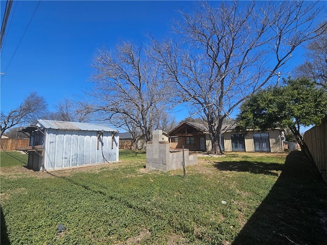 view of yard featuring an outdoor structure, fence, and a storage shed