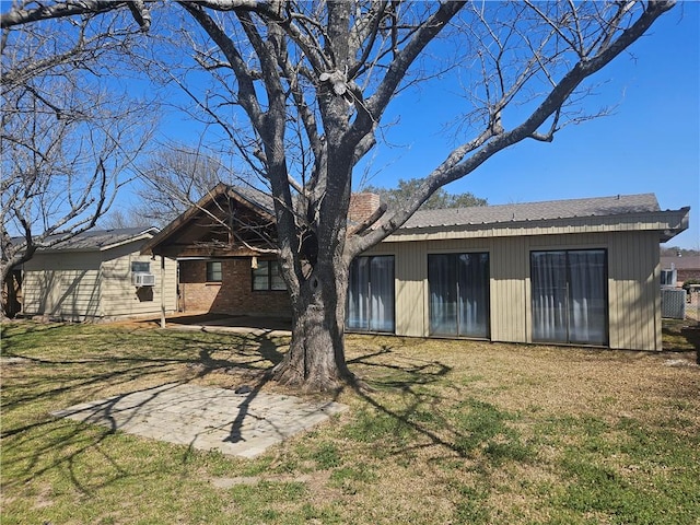 back of property with brick siding, a yard, and a patio