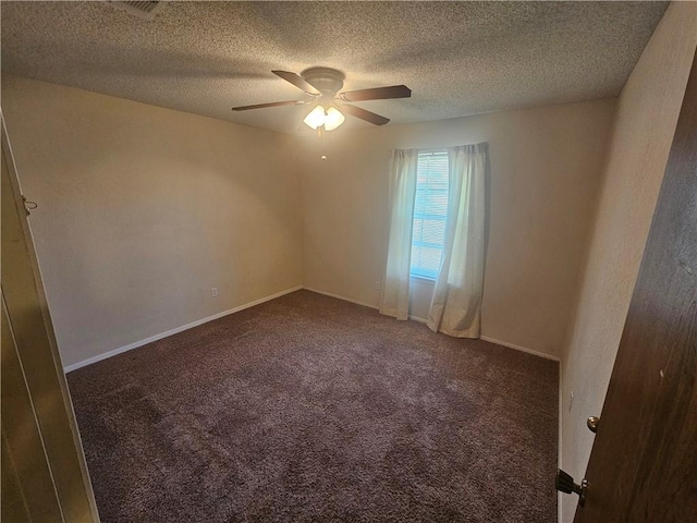 spare room with a textured ceiling, dark colored carpet, a ceiling fan, and baseboards