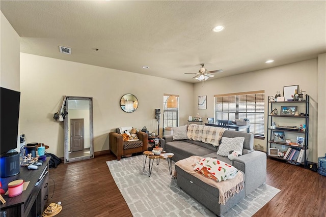 living room featuring dark wood-type flooring, a textured ceiling, and ceiling fan