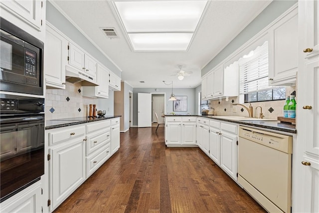 kitchen with dark countertops, a peninsula, under cabinet range hood, black appliances, and a sink